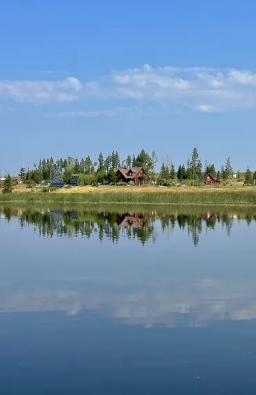 The main lodge and barn overlook Siwash Lake on a calm summer day